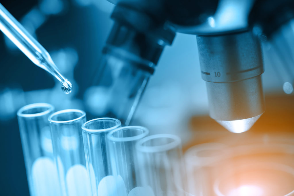 Microscope with laboratory glassware, science research and development concept, dropping chemical liquid to teat tube in lab.